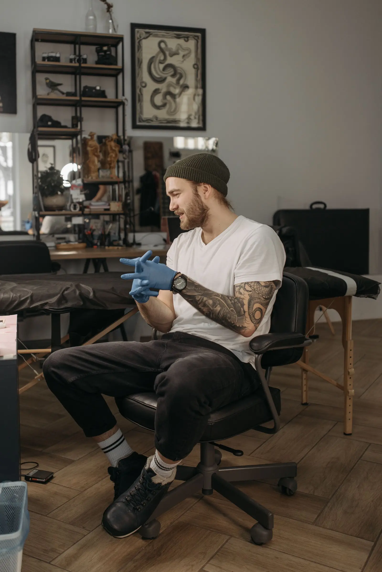Smiling tattoo artist in gloves and a beanie in his studio