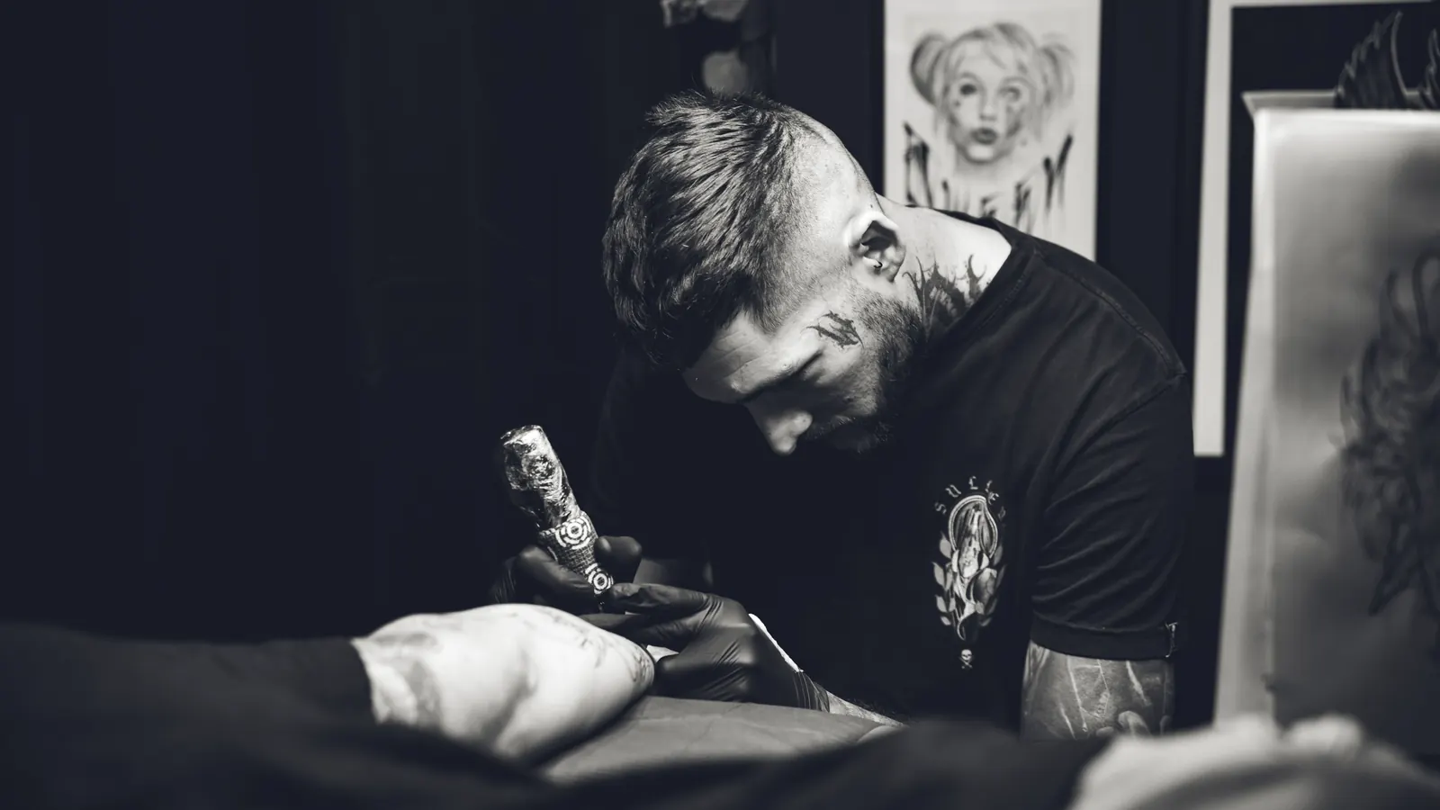 Black-and-white photo of a focused tattoo artist at work