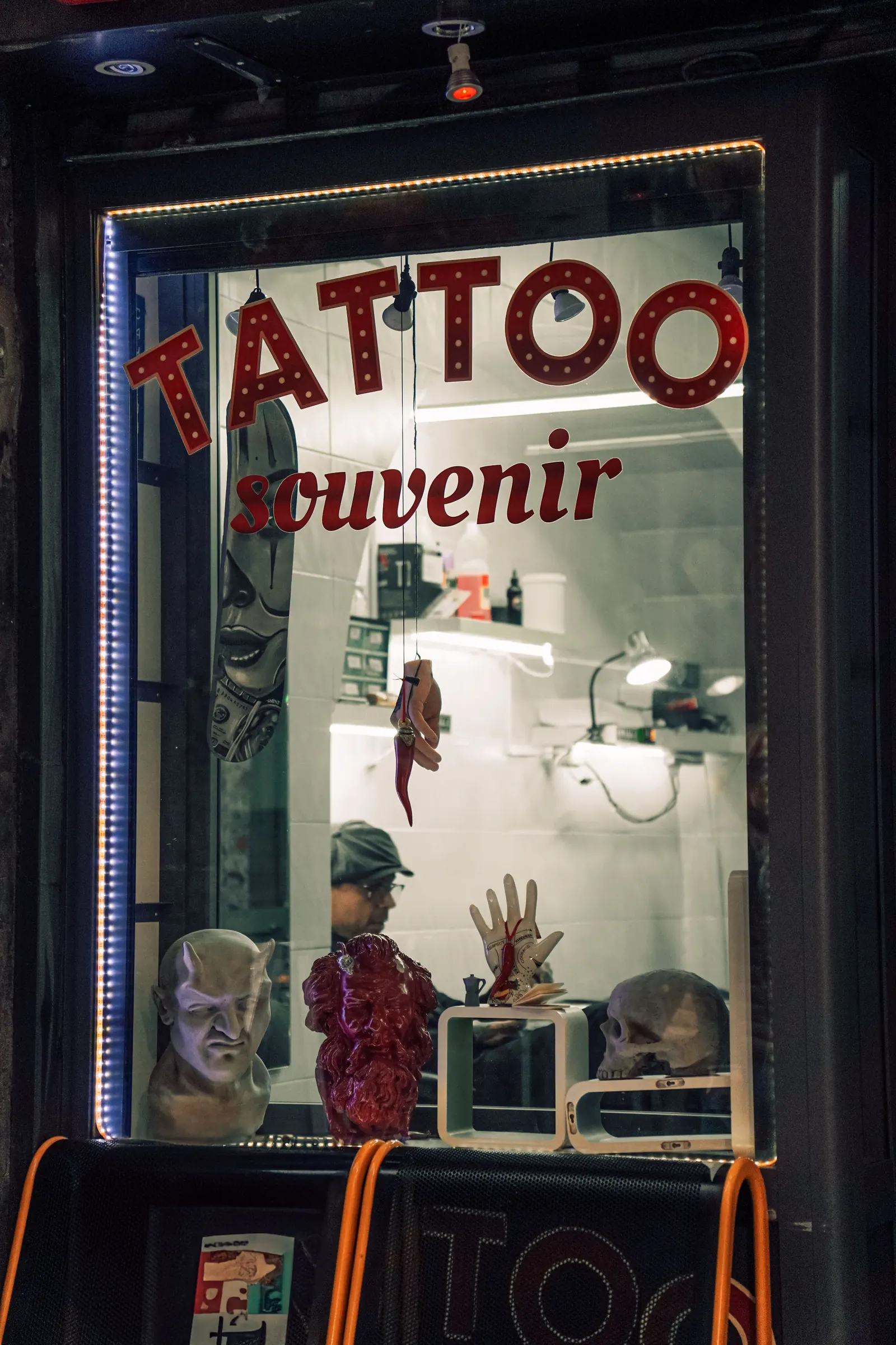 Tattoo shop window with souvenirs and a neon sign