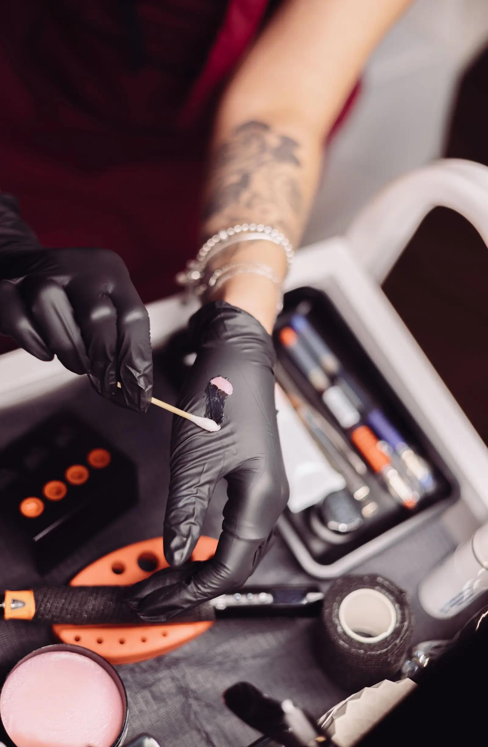 Gloved hands preparing tattoo supplies from a tool box