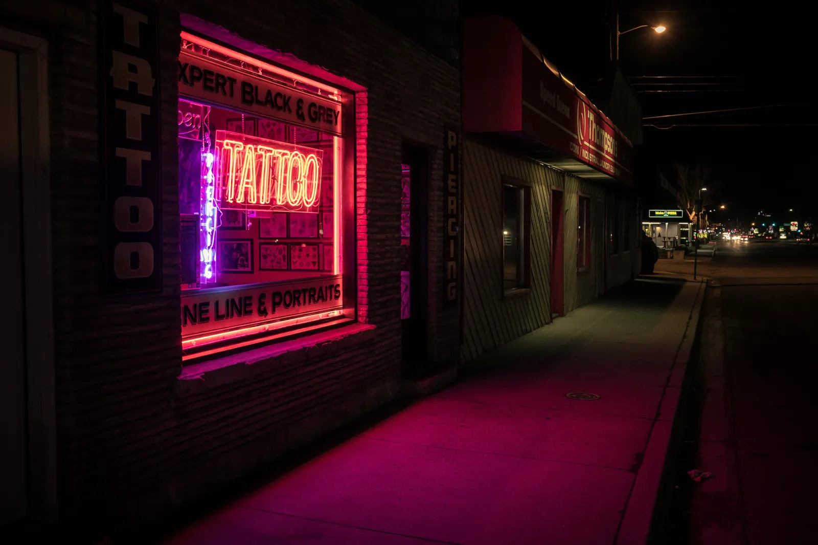 Tattoo shop front with a neon sign at night