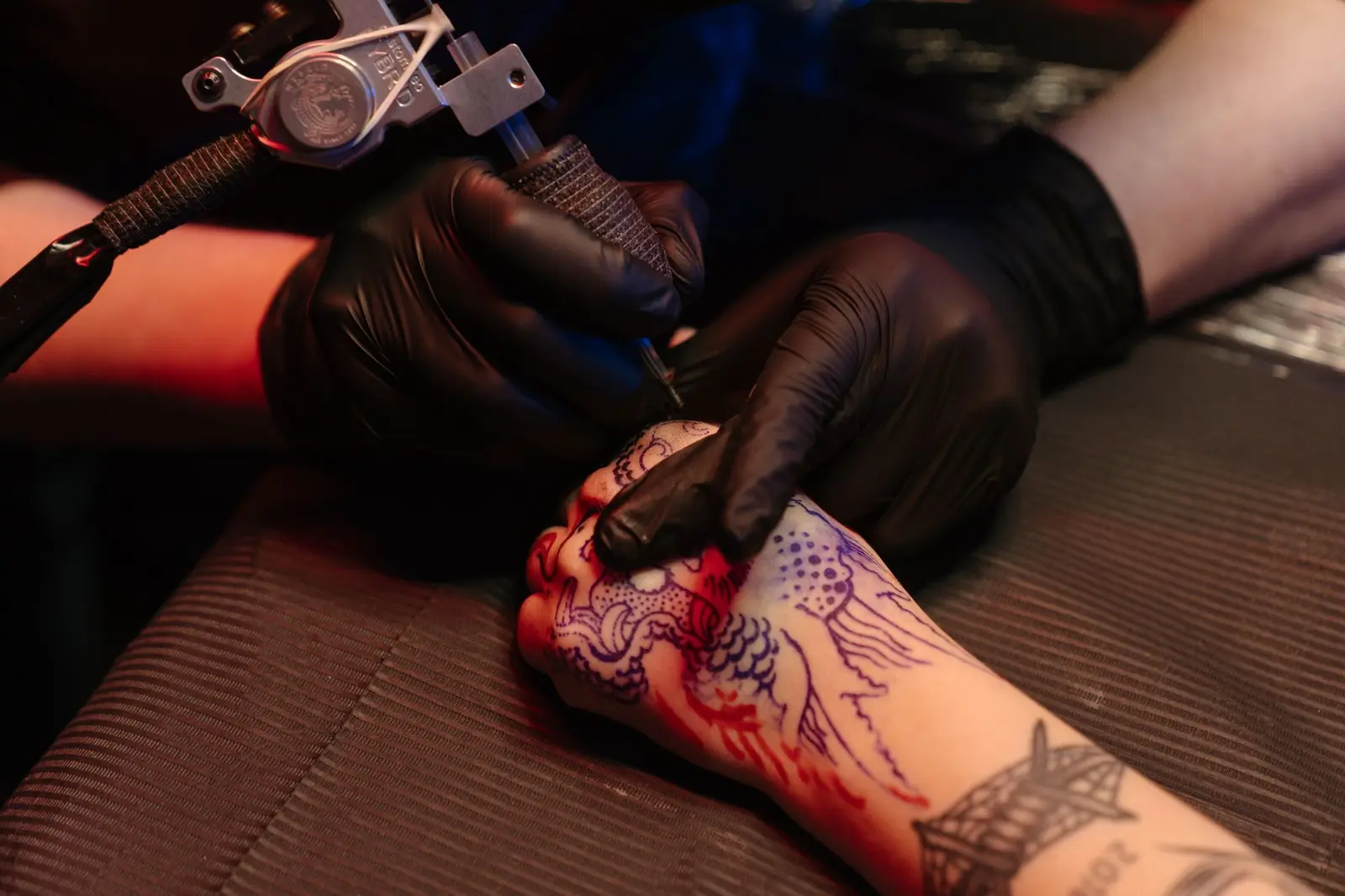 Close-up of a red rose being tattooed on an arm