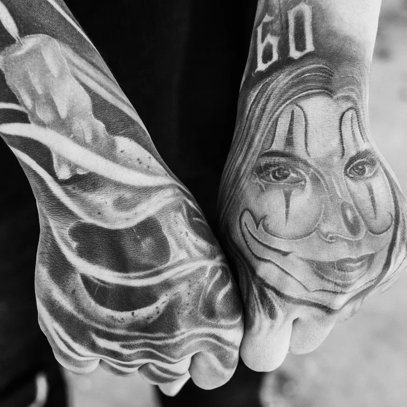 Black and grey chicano-style hand tattoos with a portrait and soft shading