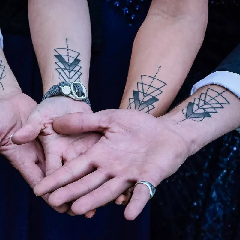 Matching geometric triangle tattoos on four wrists
