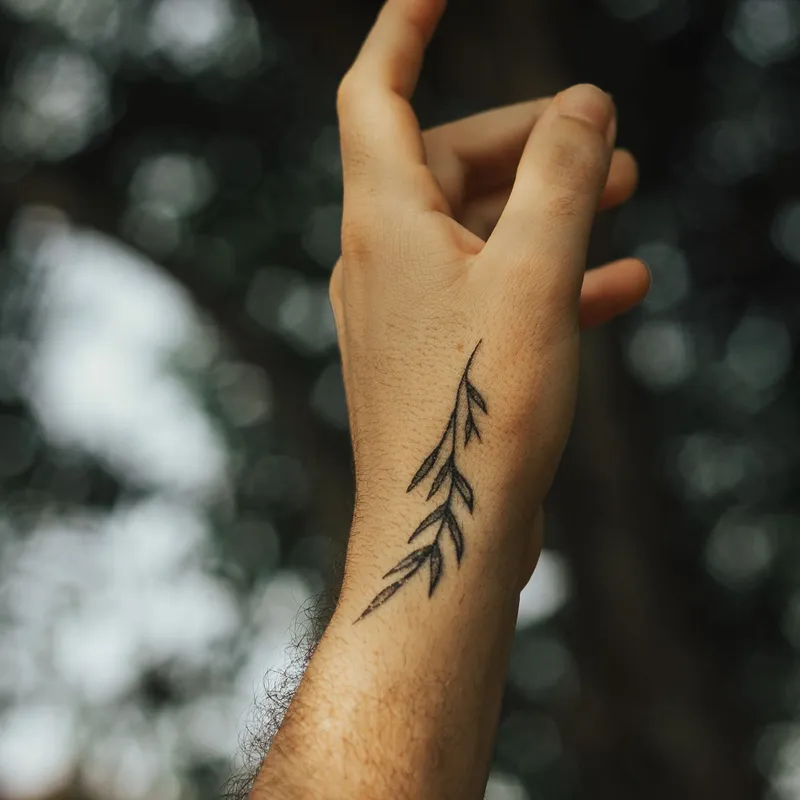 Small minimalist leaf tattoo on the side of a hand